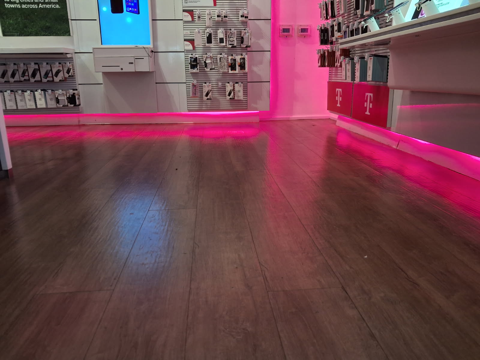 Retail store display walls and shelving with wood-grain plank flooring and accent lighting set along the baseboards
