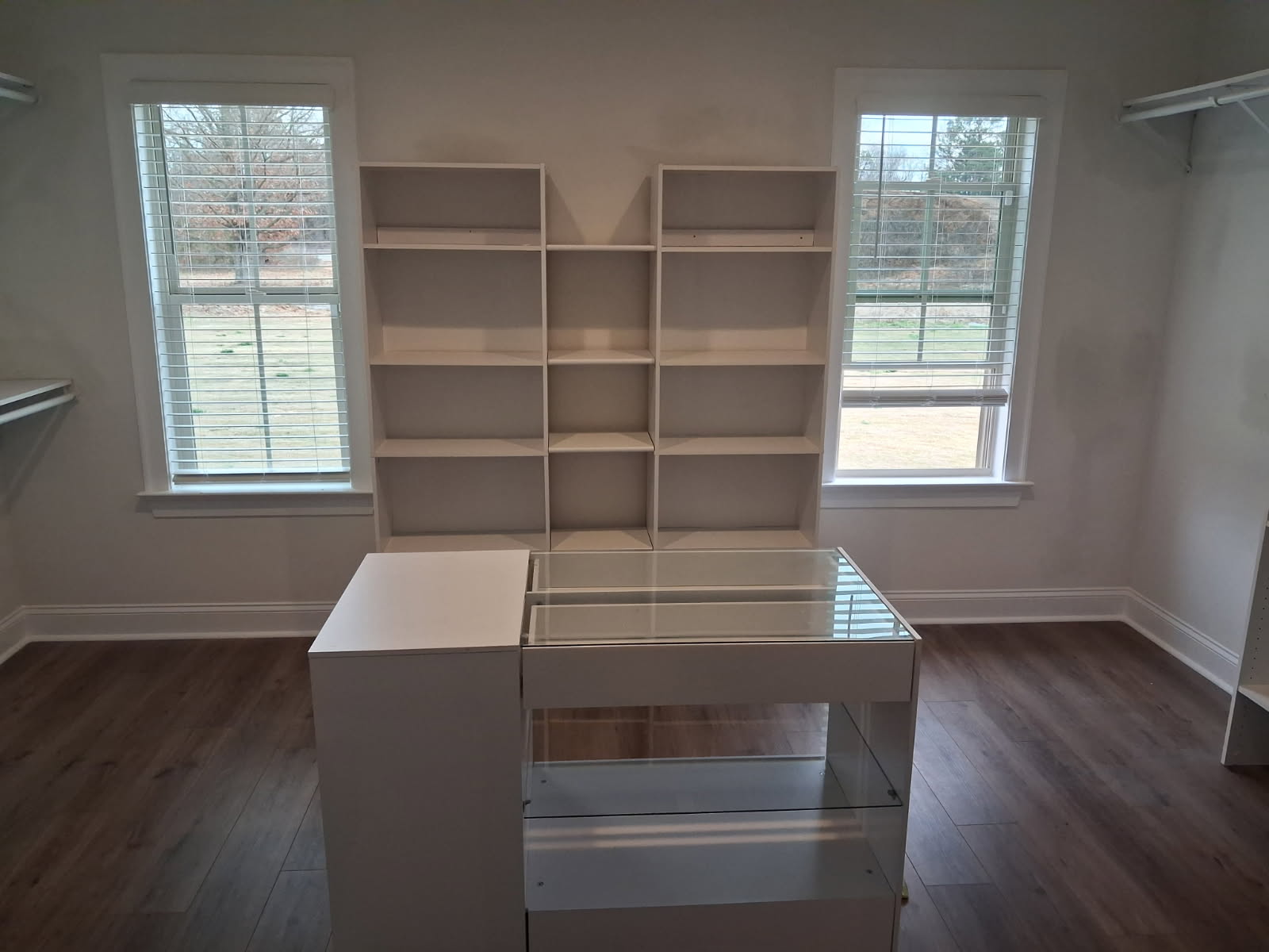 Walk-in closet with white built-in shelving and a center island with drawers under a glass top