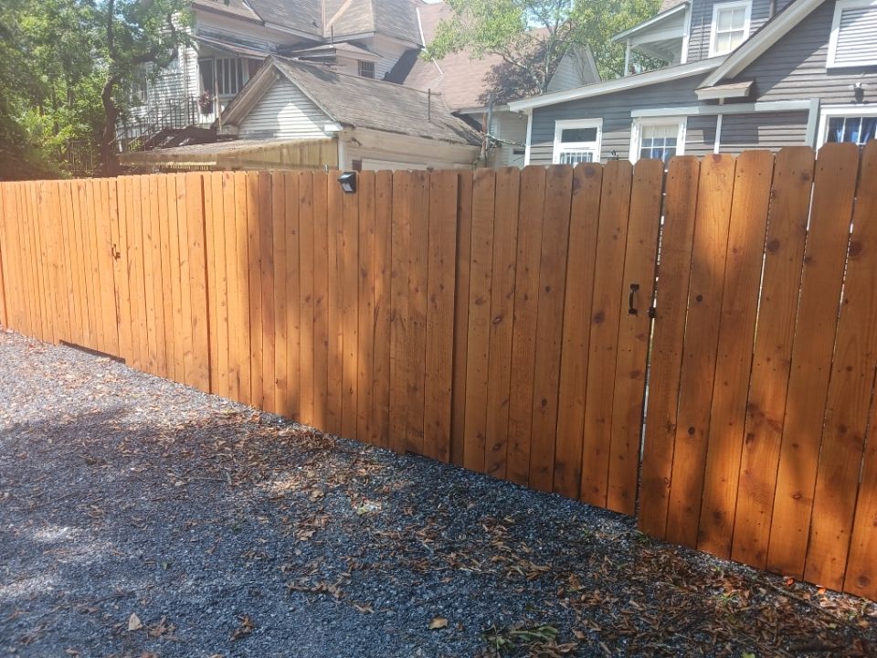 Newly built vertical-plank wooden privacy fence with a gate latch, standing in a Montgomery side yard